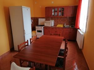 cocina con mesa de madera y nevera blanca en Sarkifény Vendégház, en Vásárosnamény