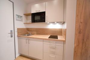 eine kleine Küche mit einer Spüle und einer Mikrowelle in der Unterkunft Boardinghouse Lingen in Lingen