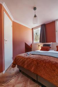 a bedroom with a large bed with orange walls at Hotel Janssen in Valkenburg