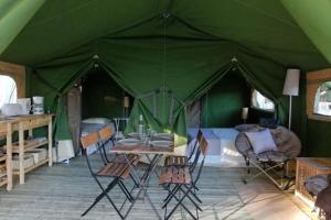 a green tent with a table and chairs in it at Camping Les Pommiers in Sotteville-sur-Mer