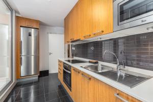 a kitchen with wooden cabinets and a stainless steel refrigerator at Dream On - Clérigos Lofts in Porto