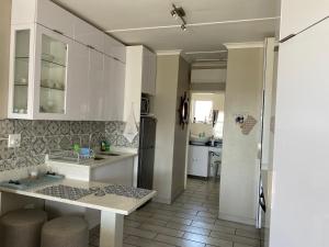 cocina con armarios blancos y encimera en Uvongo Chalet 11, en Margate