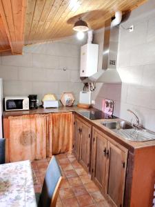 una cocina con armarios de madera y fregadero en Apartamentos El Mirador en Candeleda