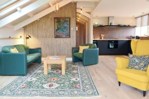 a living room with blue and yellow chairs and a rug at Vakantiehuis Noflik Nijemirdum in Nijemirdum