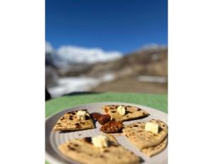 a plate of pizza with cheese and nuts on it at Dorje Camps Sarchu, Manali in Manāli