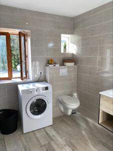 uma casa de banho com uma máquina de lavar roupa e um WC em Les orchidées em Saint-Cybranet