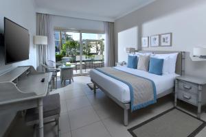 een slaapkamer met een bed, een bureau en een televisie bij Jaz Casa Del Mar Beach in Hurghada