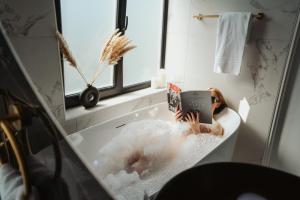 a woman sitting in a bath tub with a tablet at Hotel Janssen in Valkenburg