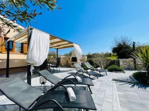 eine Gruppe von Stühlen und Sonnenschirmen auf einer Terrasse in der Unterkunft Holiday House Tesser with Pool in Galižana