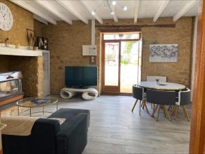 ein Wohnzimmer mit einem Tisch und einem TV in der Unterkunft Les orchidées in Saint-Cybranet