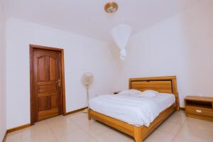 1 dormitorio con 1 cama con sábanas blancas y puerta en KAMI LUXURY APARTMENTS, en Kigali