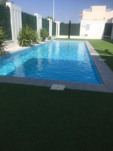 a swimming pool with blue water in a yard at Casa Escocesa in San Pedro del Pinatar