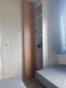 1 dormitorio con 1 cama y puerta de madera en MOBIL HOME DU ROUTIER, en Valras-Plage