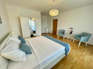 a bedroom with a large white bed and blue chairs at Apartmani Selina in Jadranovo