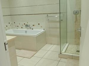 een badkamer met een douche, een bad en een wastafel bij Drakenzicht Mountain Cottage in Winterton