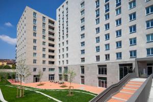 two tall buildings with a courtyard in front of them at Giovenale Milan Navigli - Modern rooms and open spaces in the heart of the city in Milan