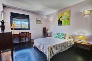- une chambre avec un lit, un bureau et une table dans l'établissement La Villa des Mainates - Jacuzzi et vue mer, à Le Tampon