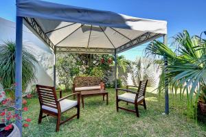 2 chaises et une table sous un parapluie bleu dans l'établissement La Villa des Mainates - Jacuzzi et vue mer, à Le Tampon