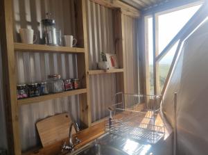 a kitchen counter with a sink and a window at Pom Gratz - EcoDomes in Hartebeest Rivier