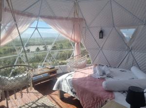 a bedroom with a bed and a large window at Pom Gratz - EcoDomes in Hartebeest Rivier