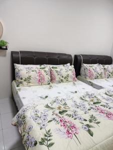 a bed with a floral comforter and pillows on it at Alyaleesya Emerald avenue 4 Brinchang for muslim in Brinchang