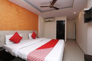 a bedroom with a large bed with red pillows at Capital O Hotel Orchid Inn in Kankhal