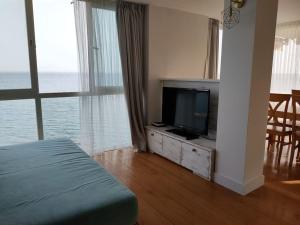 una camera da letto con televisore e tavolo con sedie di La Perla Playa a Benalmádena
