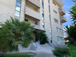 wysoki budynek z palmami przed nim w obiekcie Panoramic Sport Apartment: vista golfo di Cagliari w Cagliari