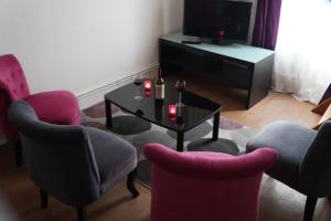 ein Wohnzimmer mit Stühlen, einem Tisch und einem TV in der Unterkunft Appartements Victor et Hugo in Bordeaux