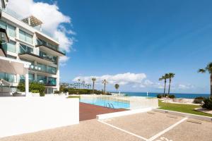 a building with a swimming pool next to the ocean at Apartment Marisol - Beachfront in Protaras