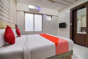 a bedroom with a large white bed with red pillows at Sunshine Inn Near Pune Railway Station in Pune