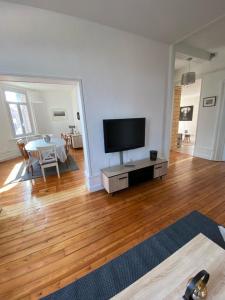 a living room with a flat screen tv and a table at Le relais des trois châteaux in Flixecourt