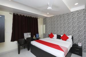a bedroom with a bed with red pillows and a chair at Flagship Richa Grand Inn Near Sahara Ganj Mall in Lucknow