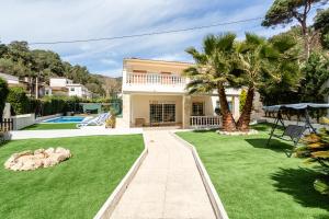 eine Villa mit einem Garten und einem Pool in der Unterkunft Ainara Luxury in Lloret de Mar