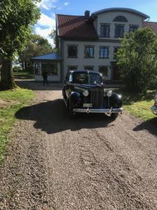 Sjötorps Säteris 1600-tals Huvudbyggnad في Larv: سيارة سوداء قديمة متوقفة أمام منزل