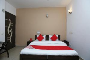 1 dormitorio con 1 cama grande con almohadas rojas en OYO Mahak Residency, en Gurgaon