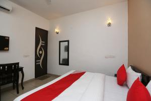 1 dormitorio con cama blanca y almohadas rojas en OYO Mahak Residency, en Gurgaon