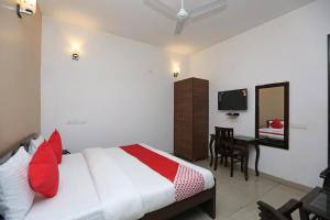 1 dormitorio con cama, escritorio y espejo en OYO Mahak Residency, en Gurgaon
