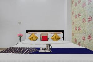 ein Schlafzimmer mit einem weißen Bett mit gelben und blauen Kissen in der Unterkunft SPOT ON Hotel Srb in Jodhpur