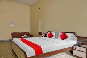 a bedroom with a large bed with red and white pillows at Hotel O Arjun in Prayagraj