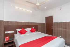 1 dormitorio con 1 cama grande con almohadas rojas en Capital O Hotel Srinivasa Residency en Tirupati