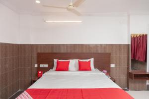 a bedroom with a large bed with red pillows at Capital O Hotel Srinivasa Residency in Tirupati