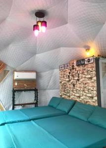 Habitación con sofá azul y pared de piedra. en Liwa-Liw Beach Villas & Dome Glamping en San Felipe