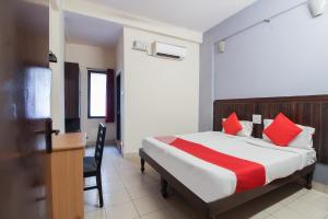 a bedroom with a bed with red pillows and a desk at OYO Hotel Regal Near Paradise Circle in Secunderabad