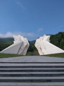 two large white sculptures on top of a hill at Tratinčica in Tjentište