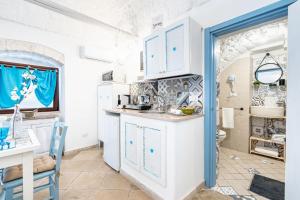 una cocina con armarios blancos y una puerta azul en Vico di Ostuni Apartments by Rentbeat, en Ostuni