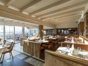 um restaurante com mesas, cadeiras e janelas em Hotel Panorama Royal em Bad Häring