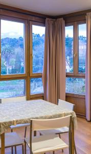 a dining room with a table and chairs and windows at Apartamentos Camparina in Llanes