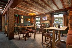 een restaurant met houten tafels, stoelen en ramen bij Harbour Inn in Porthleven