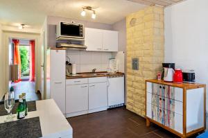 Una cocina con gabinetes blancos y un refrigerador blanco. en Fischerstube, en Sipplingen